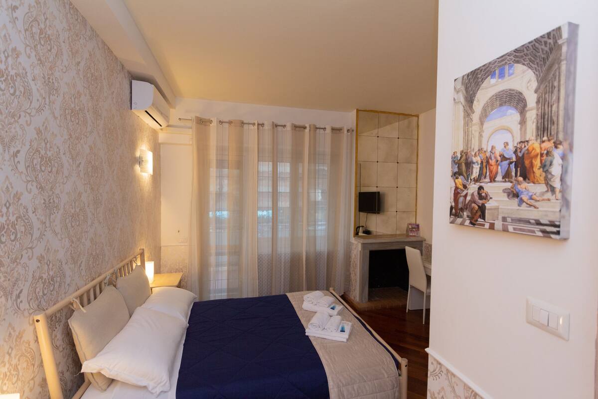 Ein Hotelzimmer mit Bett, Schreibtisch und einem Bild an der Wand.