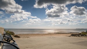 A beach with a concrete walkway and metal benches.