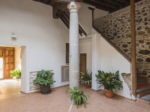 A spacious interior with a stone staircase, a central column, and potted plants.
