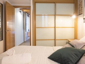 A bedroom with a bed, a wooden wardrobe, and a nightstand.