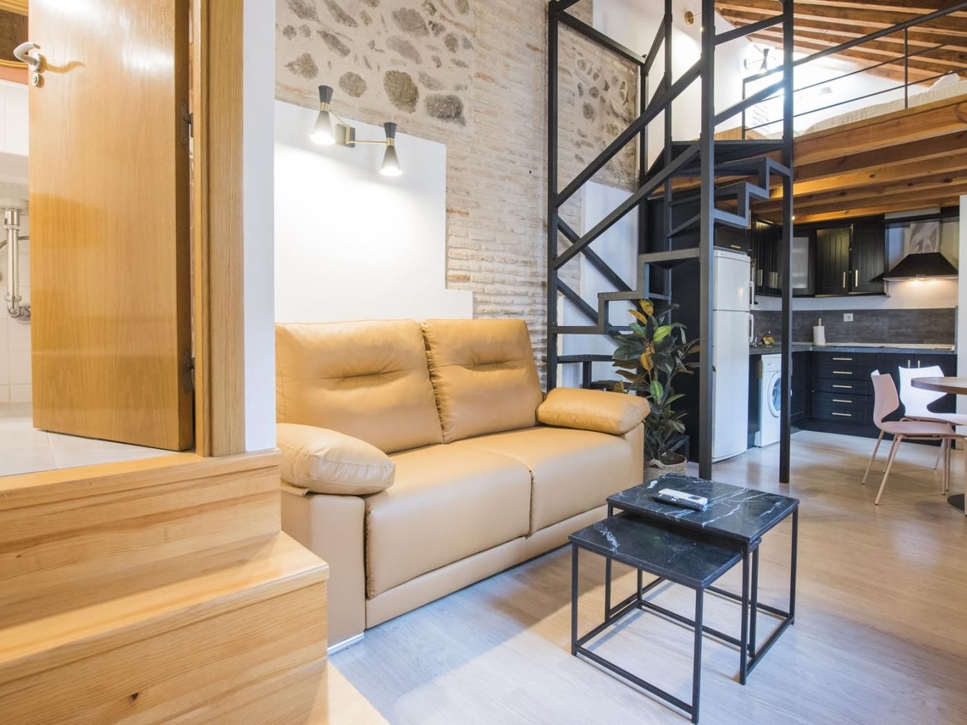 A modern living room with a sofa, a coffee table, and a staircase leading to an upper level.
