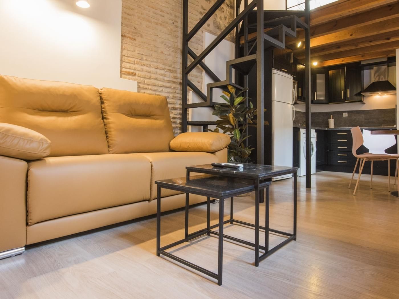 A modern living room with a sofa, a coffee table, and a kitchen area in the background.