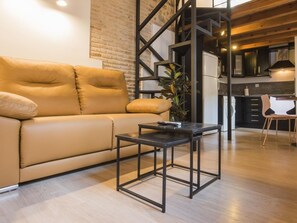 A modern living room with a sofa, a coffee table, and a kitchen area in the background.