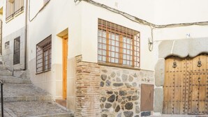 Una stretta via acciottolata con un muro in pietra e una porta in legno.