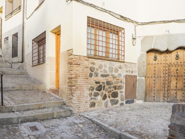 A narrow cobblestone street with a stone wall and a wooden door.