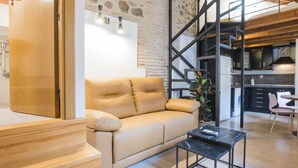 Un soggiorno moderno con un divano, un tavolino da caffè e una scala che conduce a una zona cucina.