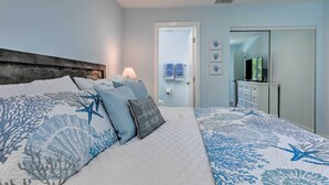 A bedroom with a large bed, a wooden headboard, a bedside table with a lamp, and a dresser with a mirror. - Holmes Beach Retreat: Walk to Beach & Dining! (Holmes Beach)
