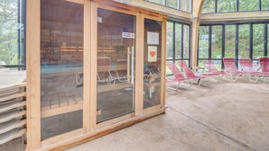 Een overdekt buitengebied met houten banken en een glazen omheining met een bordje.