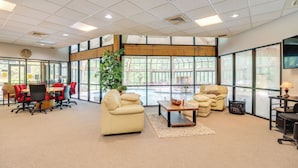Een ruime vergaderruimte met een grote tafel, verschillende stoelen, een bank en een bijzettafeltje.