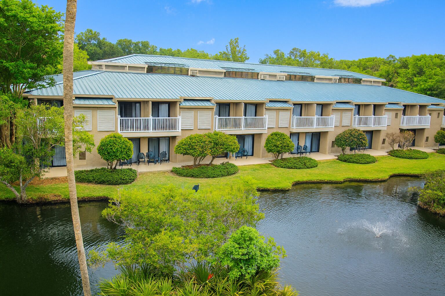 A multi-story hotel with a green roof, outdoor seating, and a water feature.