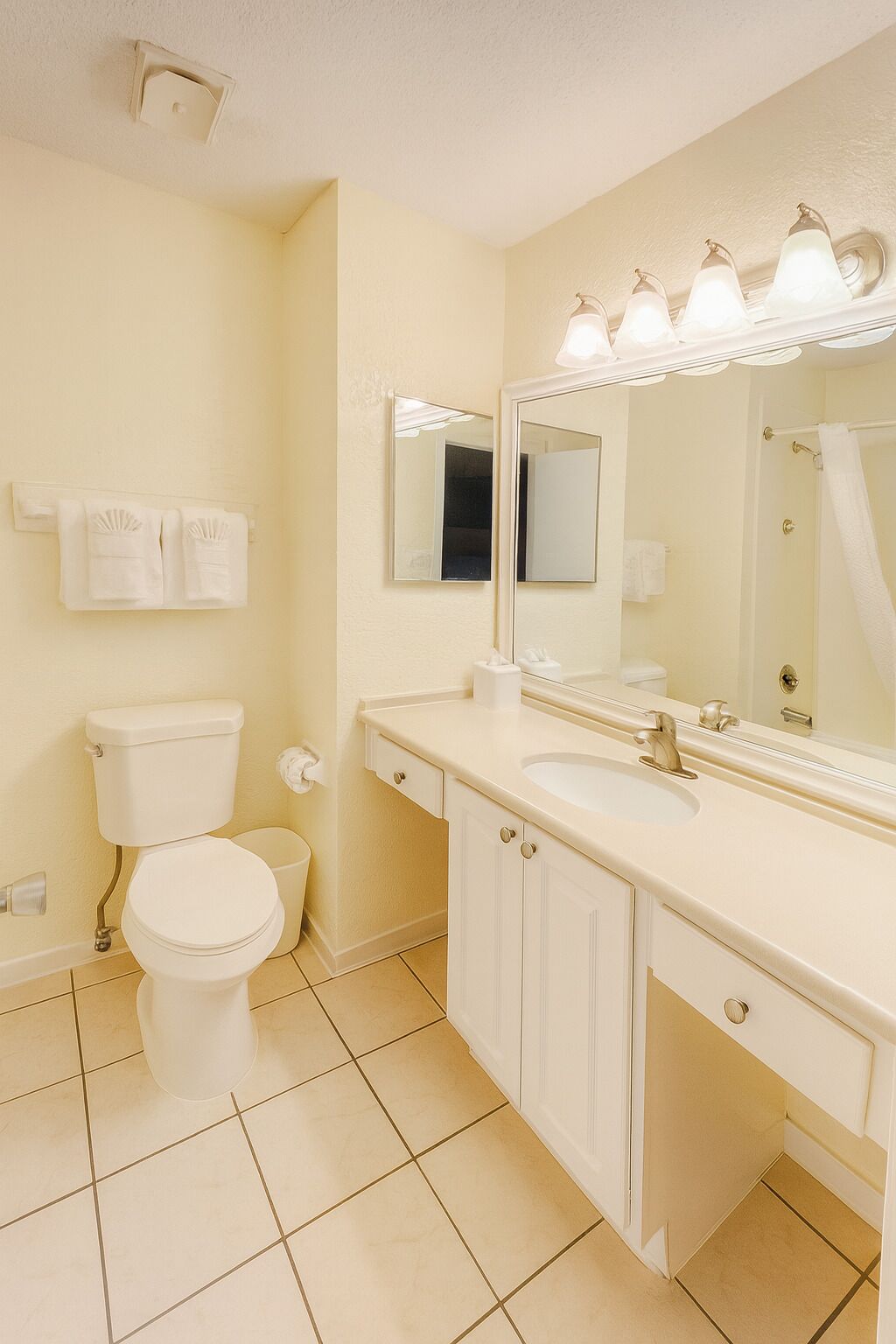 Un baño con inodoro, lavamanos, espejo y toallero.