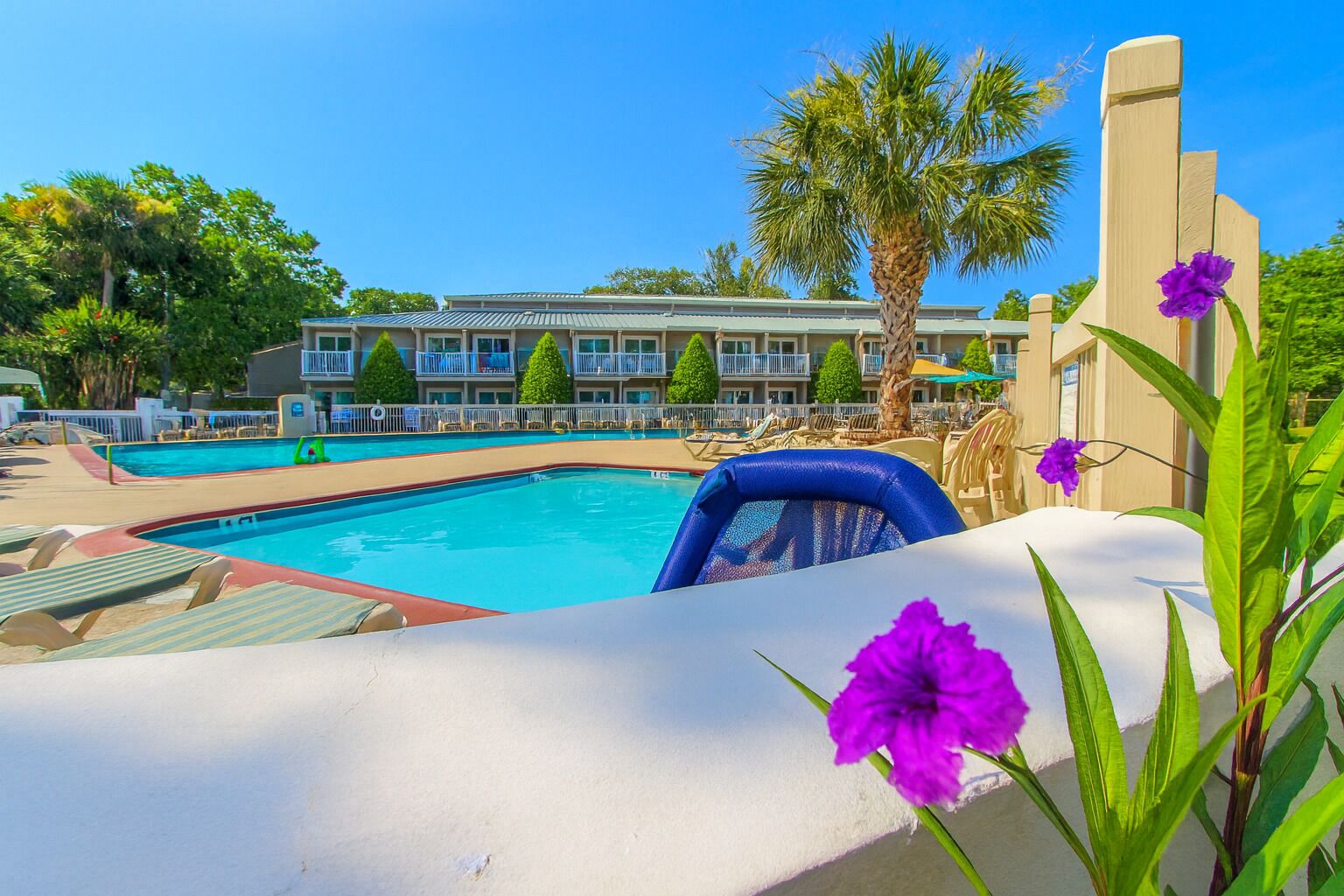 A swimming pool with lounge chairs and a building in the background.