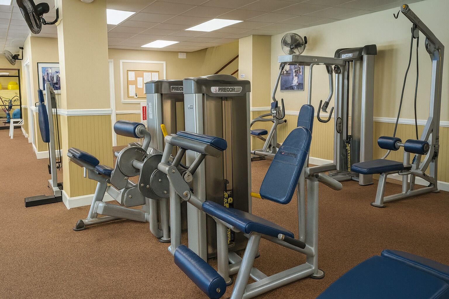 A gym with various exercise machines, including weight benches and a cable machine.