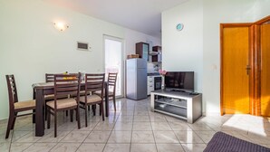 Un espacio habitable compacto con comedor, kitchenette y televisor.