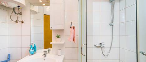 A modern bathroom with a sink, mirror, and shower.