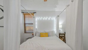 Ein Schlafzimmer mit einem Bett, einem Nachttisch und einem Fenster mit Jalousien.