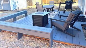 Eine Terrasse mit Tisch und Stühlen, umgeben von einem Holzdeck und einem Garten.