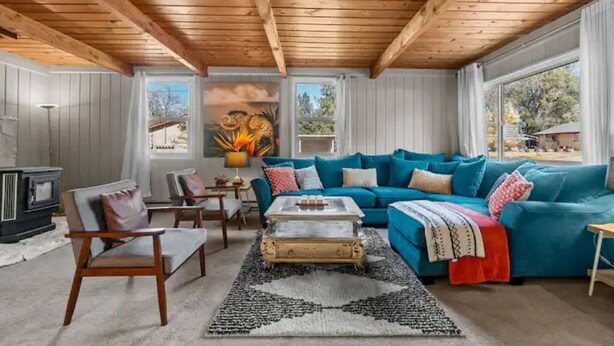 A cozy living room with a blue sofa, wooden ceiling beams, a vintage coffee table, and a fireplace. - Heart of Bend-Walkable, Ping Pong, Billards (Bend)