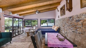 A spacious room with a stone wall, a bed, a table with a pink checkered tablecloth, and a green sofa. - Istrian Tavern with Shared Pool (Banjole)