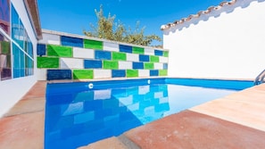 Una piscina con un muro revestido de azulejos con un diseño geométrico.