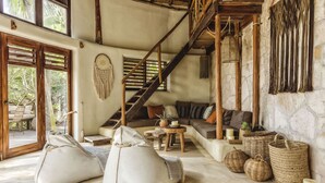 A spacious living area with a staircase, comfortable seating, and natural light from large windows. - CASA ZABA (Tulum)