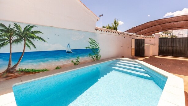 A swimming pool with a mural of a beach scene, including palm trees and a sailboat.