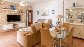A living room with a sofa, TV, and dining table with chairs.
