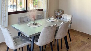 A dining area with a table and six chairs, a decorative centerpiece, and a window with curtains. - Villa Ortega Alba Alcalá La Real by Ruralidays (Jaén)