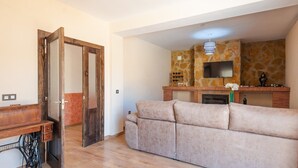 A living room with a beige sofa, a wooden cabinet, and a stone fireplace. - Villa Ortega Alba Alcalá La Real by Ruralidays (Jaén)
