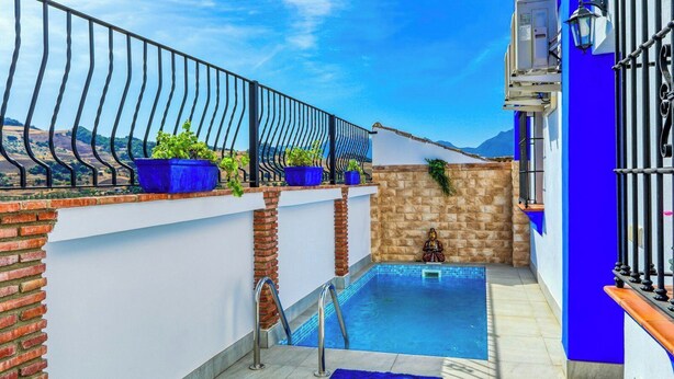 A rooftop pool with a blue-tiled floor, a small statue, and a view of the mountains. - Casa de Teones con piscina privada Montecorto by Ruralidays (Málaga)