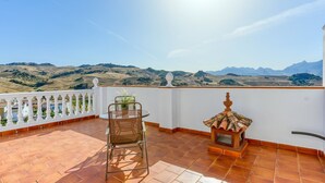 A terrace with a table and chair, a decorative lantern, and a view of distant hills. - Casa de Teones con piscina privada Montecorto by Ruralidays (Málaga)