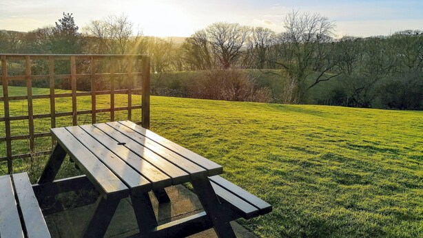 A picnic table with a view of a grassy field and trees in the background. - Cosy cottage with designated parking. (Whitby)
