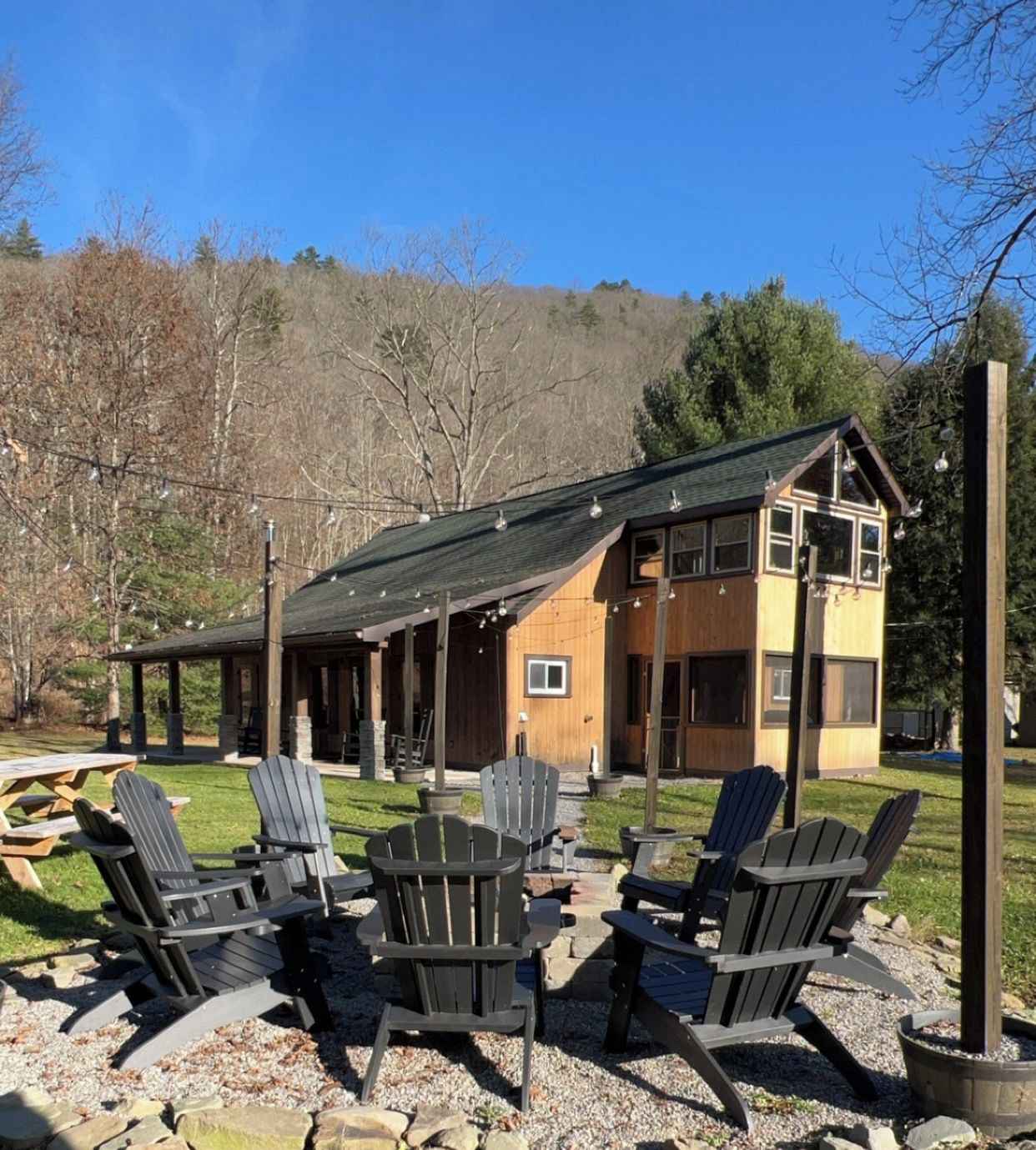 Un lodge con veranda coperta, posti a sedere all'aperto e vista su una collina boscosa.