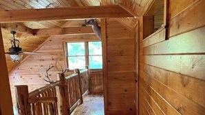 A wooden interior with a sloped ceiling, a wooden staircase, and a window providing natural light.