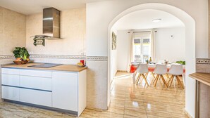 A modern kitchen with a central island, white cabinetry, and a stainless steel range hood. - Stunning air conditioned House (Cijuela)