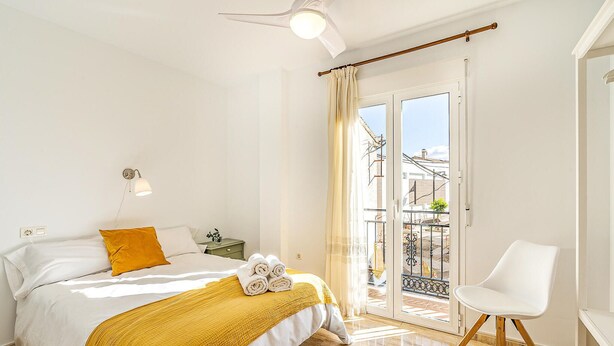 A hotel room with a bed, a bedside lamp, a chair, and a balcony with a view. - Stunning air conditioned House (Cijuela)