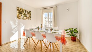 A dining area with a table set for four, white chairs, a potted plant, and a painting on the wall. - Stunning air conditioned House (Cijuela)