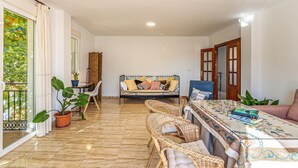 A spacious living area with a sofa, wicker chairs, a glass-top coffee table, and a potted plant. - Stunning air conditioned House (Cijuela)