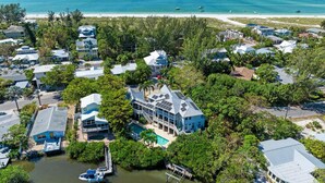 Vista aérea de una zona residencial costera con casas, una playa y un puerto deportivo.