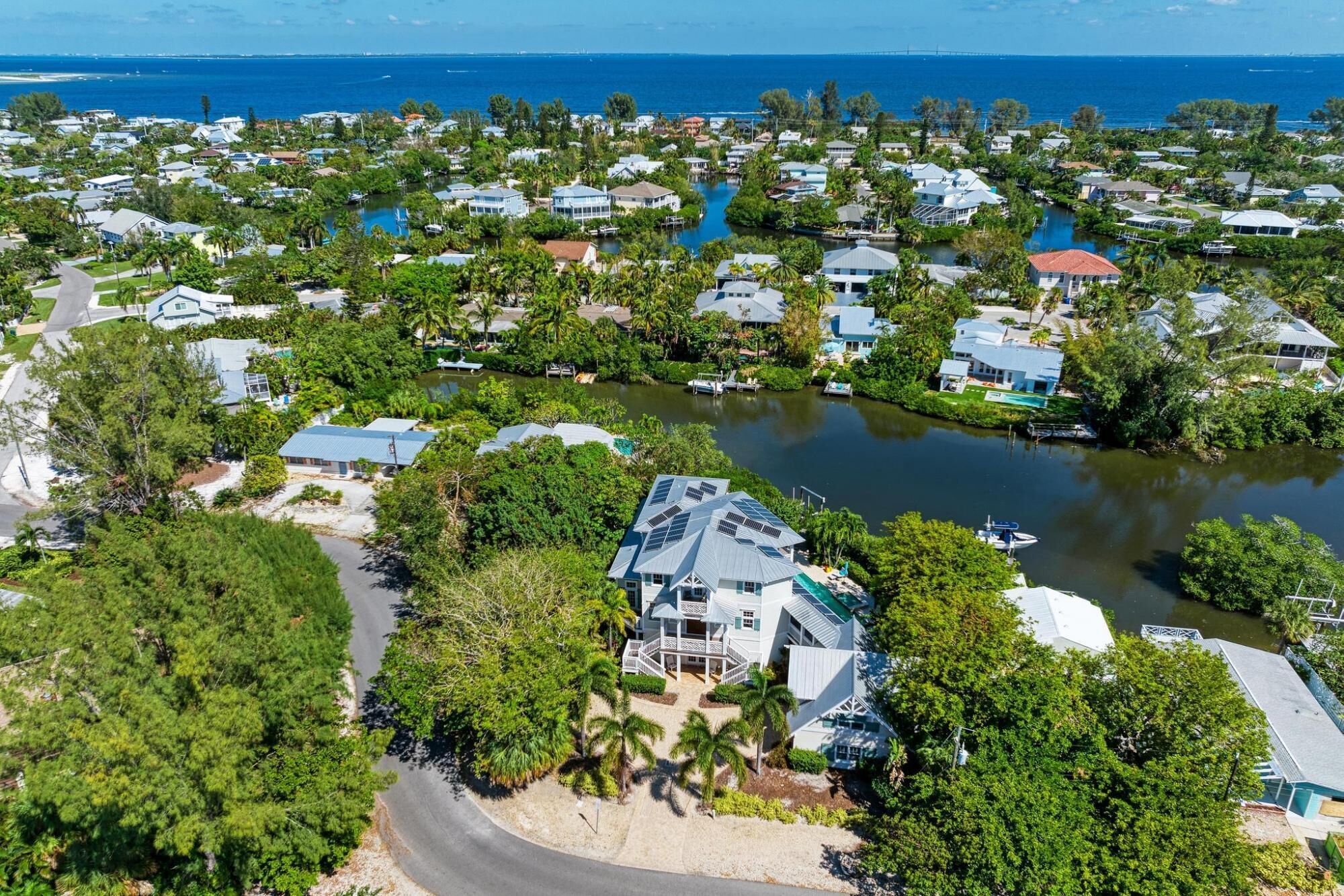An aerial view of a coastal residential area with houses, a marina, and a large body of water.