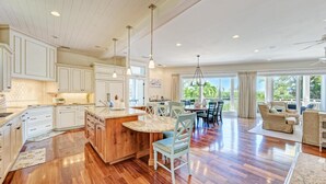 Una cocina amplia con armarios blancos, una isla grande y un comedor con vistas al exterior.