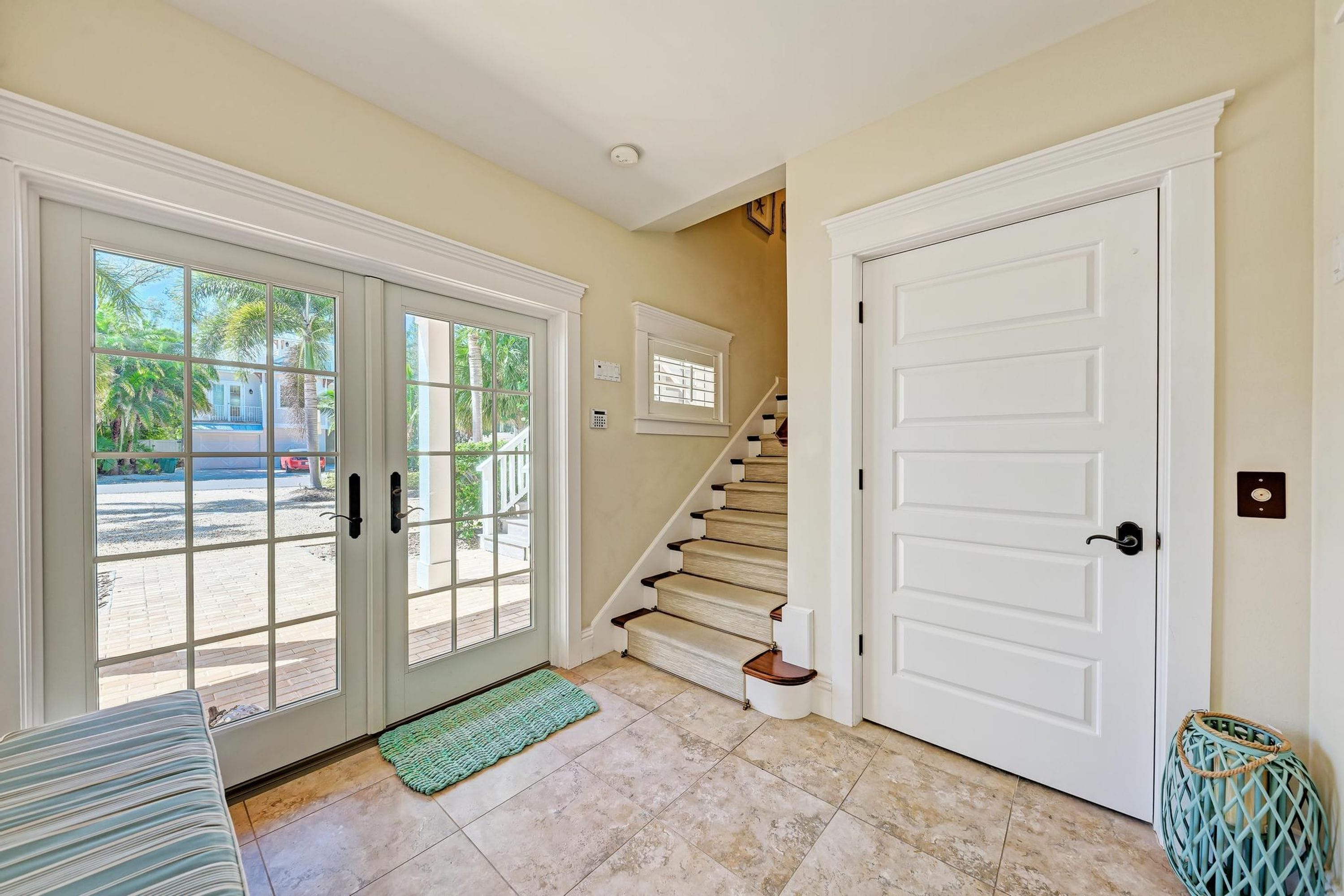 A hallway with a staircase, a door, and a view of the outside.