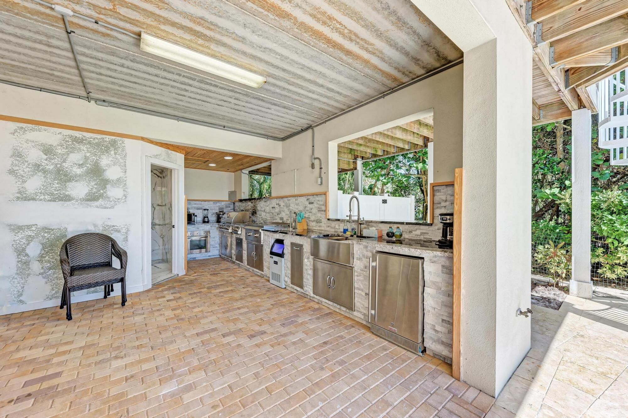 A spacious kitchen with a stone backsplash, modern appliances, and a view of greenery.