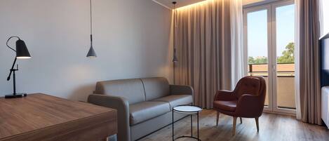 A modern living room with a wooden table, a sofa, a small round table, a chair, and a large window with curtains.
