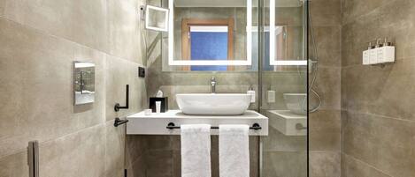 A modern bathroom with a glass-enclosed shower, a white sink, and a toilet.