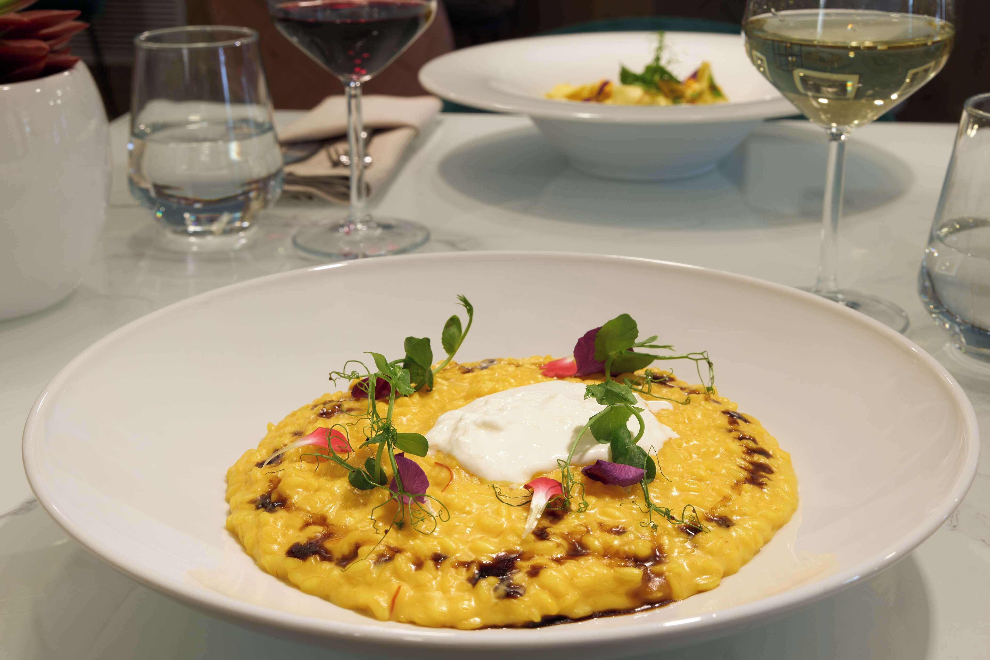 A plate of food with a creamy yellow dish, garnished with greens and a dollop of cream.
