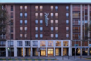 Un hotel con un llamativo letrero de 'Radisson', numerosas ventanas y una entrada a nivel de calle con un letrero 'MED' que indica servicios médicos.