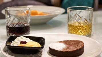 Un plato de postre con pastel de chocolate y una pequeña fuente de crema batida y fruta.