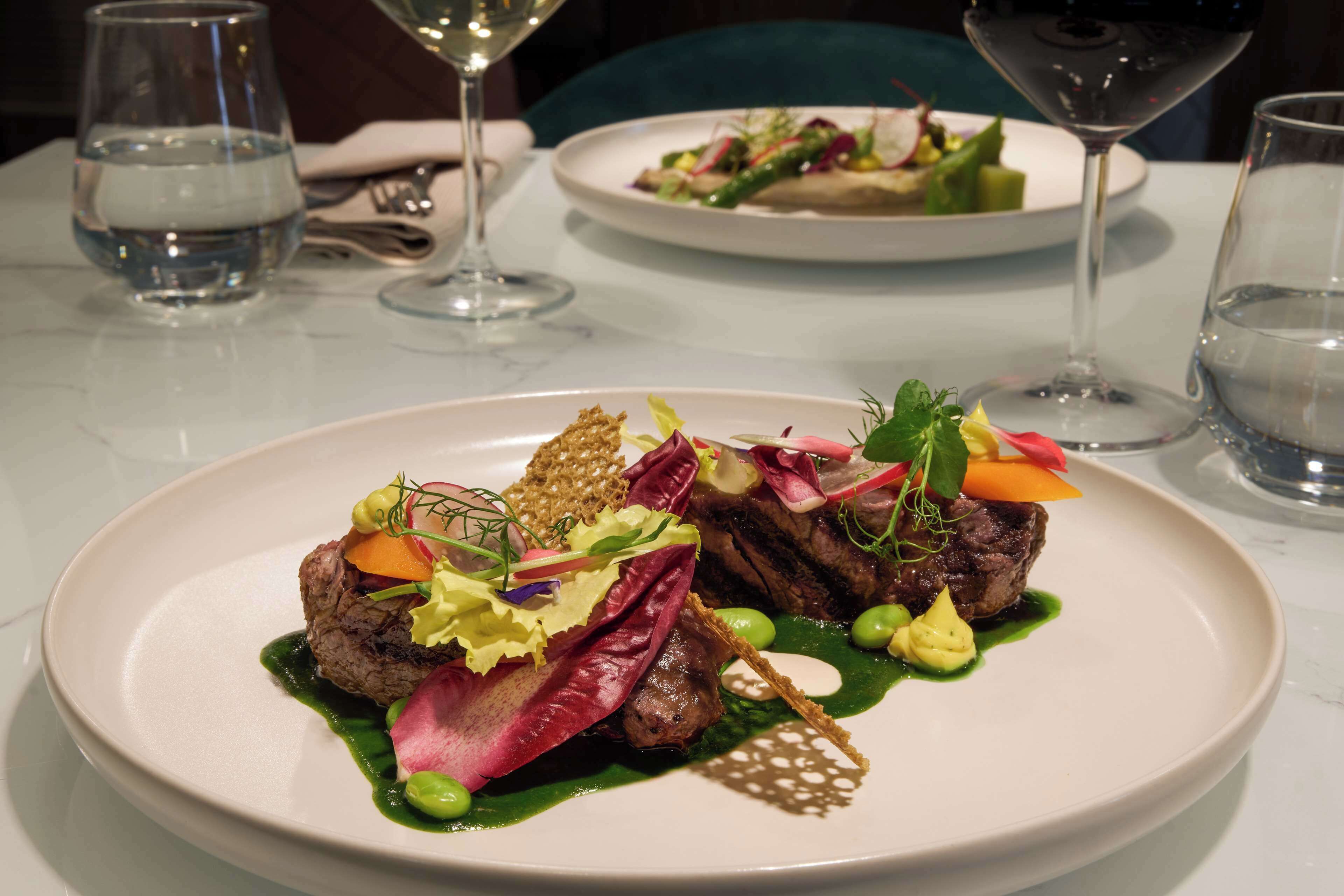 Ein Esstisch mit Tellern voller Essen, Gläsern mit Wasser und Besteck.