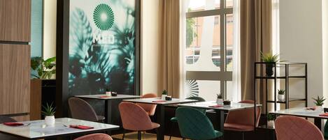 Habitación de hotel moderna con un amplio ventanal, una pantalla de proyección mostrando un logotipo y diversas opciones de asiento.